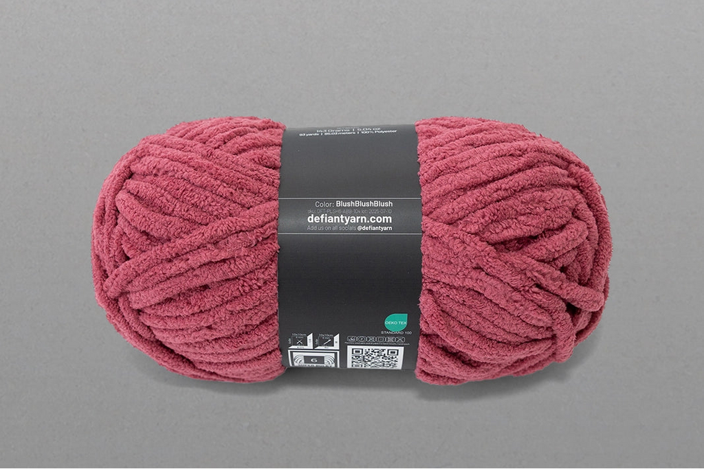 Pink skein of yarn with a label on a gray background