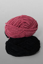 Two balls of yarn, one pink and one black, on a gray background