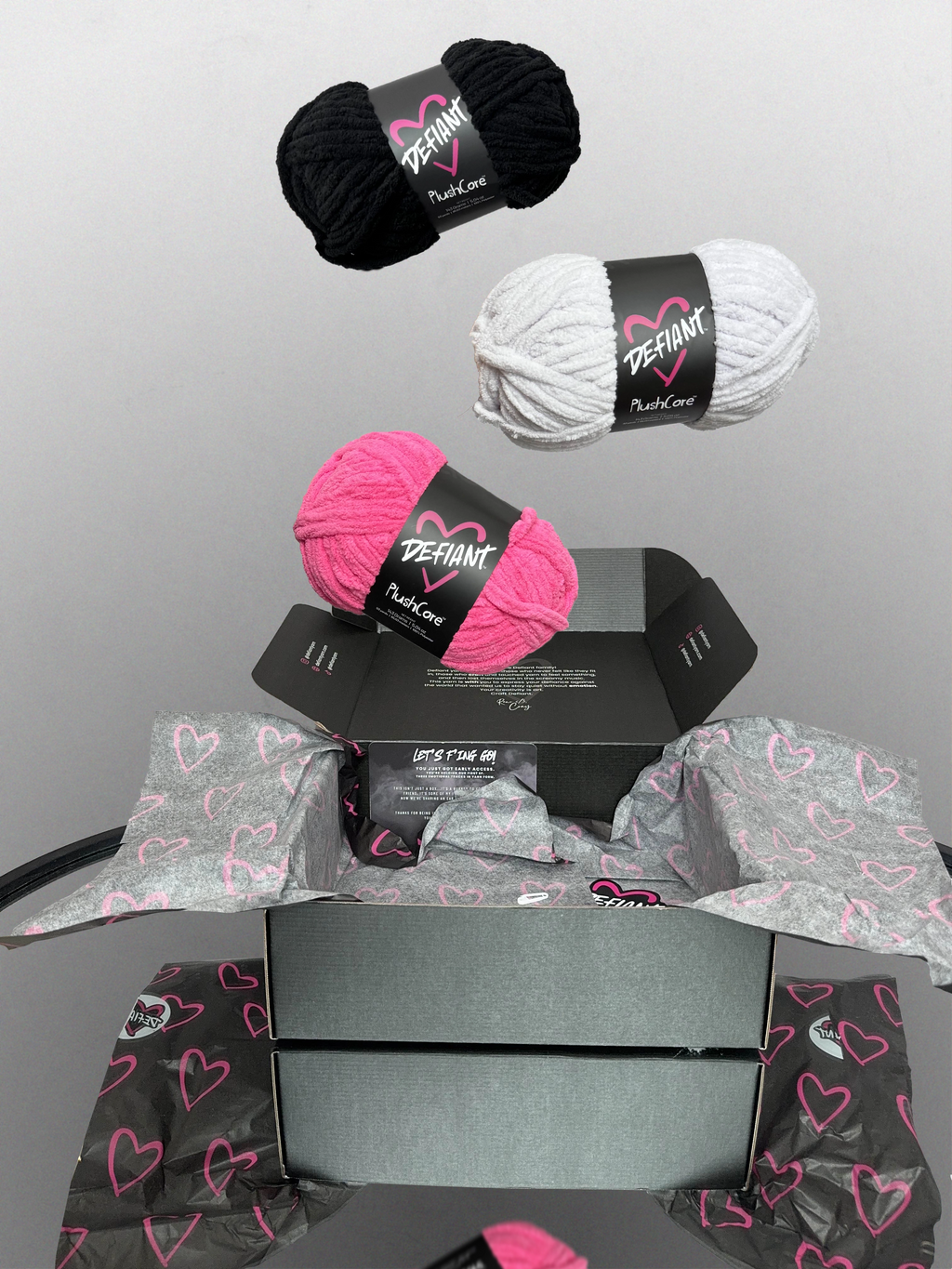 Yarn balls with 'Defiant' labels on a gray background