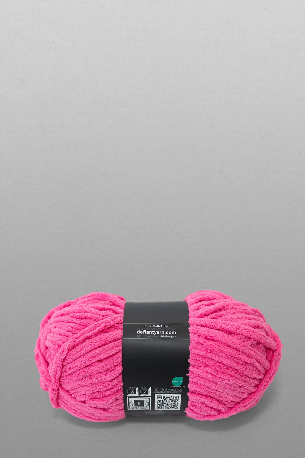 Pink yarn ball with a label on a gray background