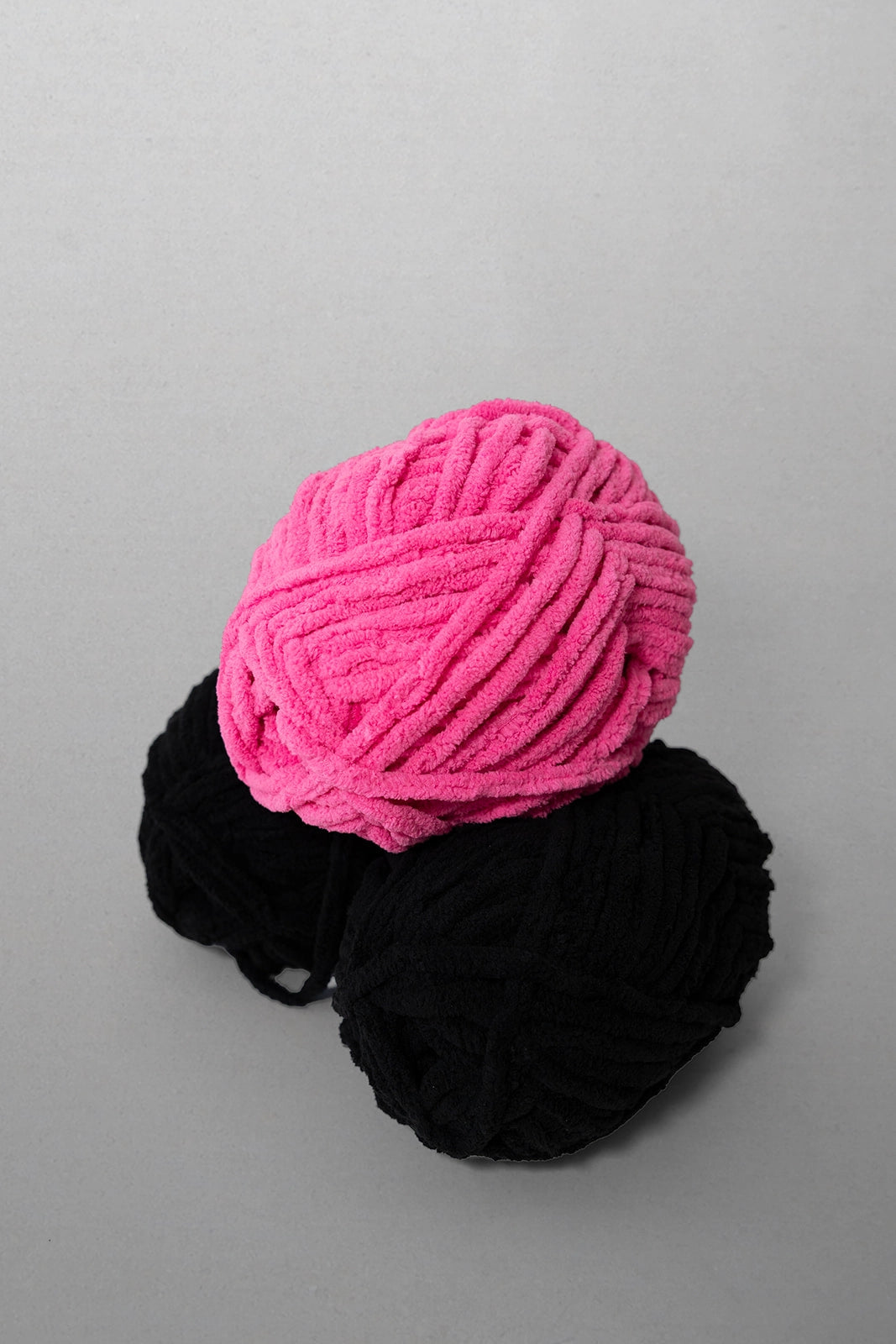 Pink and black yarn balls on a gray background
