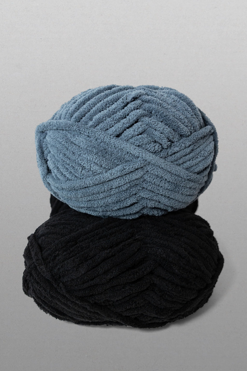 Two balls of yarn, one blue and one black, on a gray background