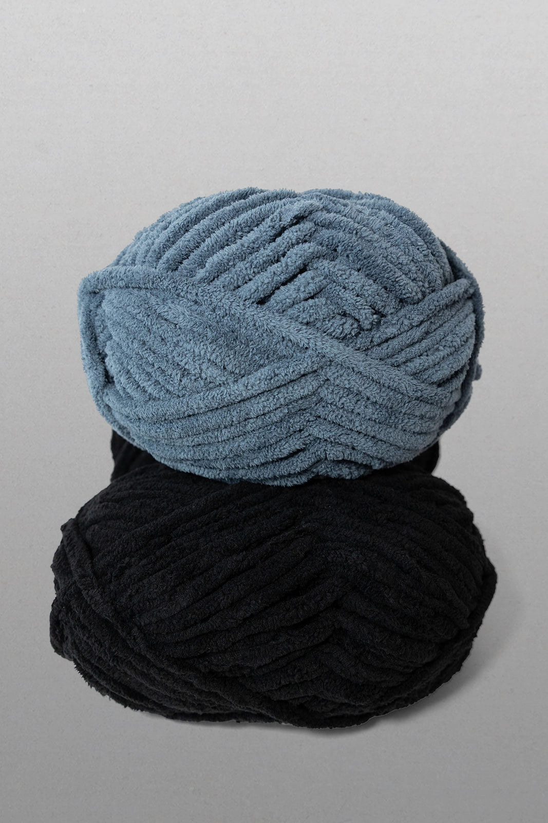 Two balls of yarn, one blue and one black, on a gray background